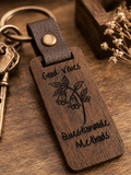 Good Vibes keychain in dark rustic wood with engraved botanical illustration and lettering, leather loop and brass hardware