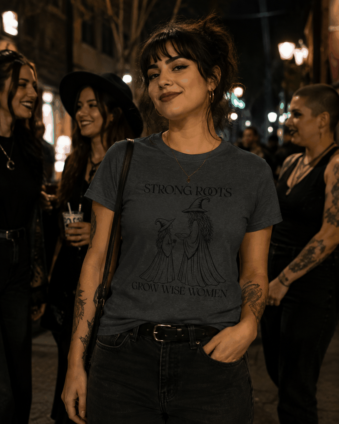 Strong Roots Grow Wise Women T-shirt, Dark Heather tee modeled indoors with adult-and-young-witch illustration