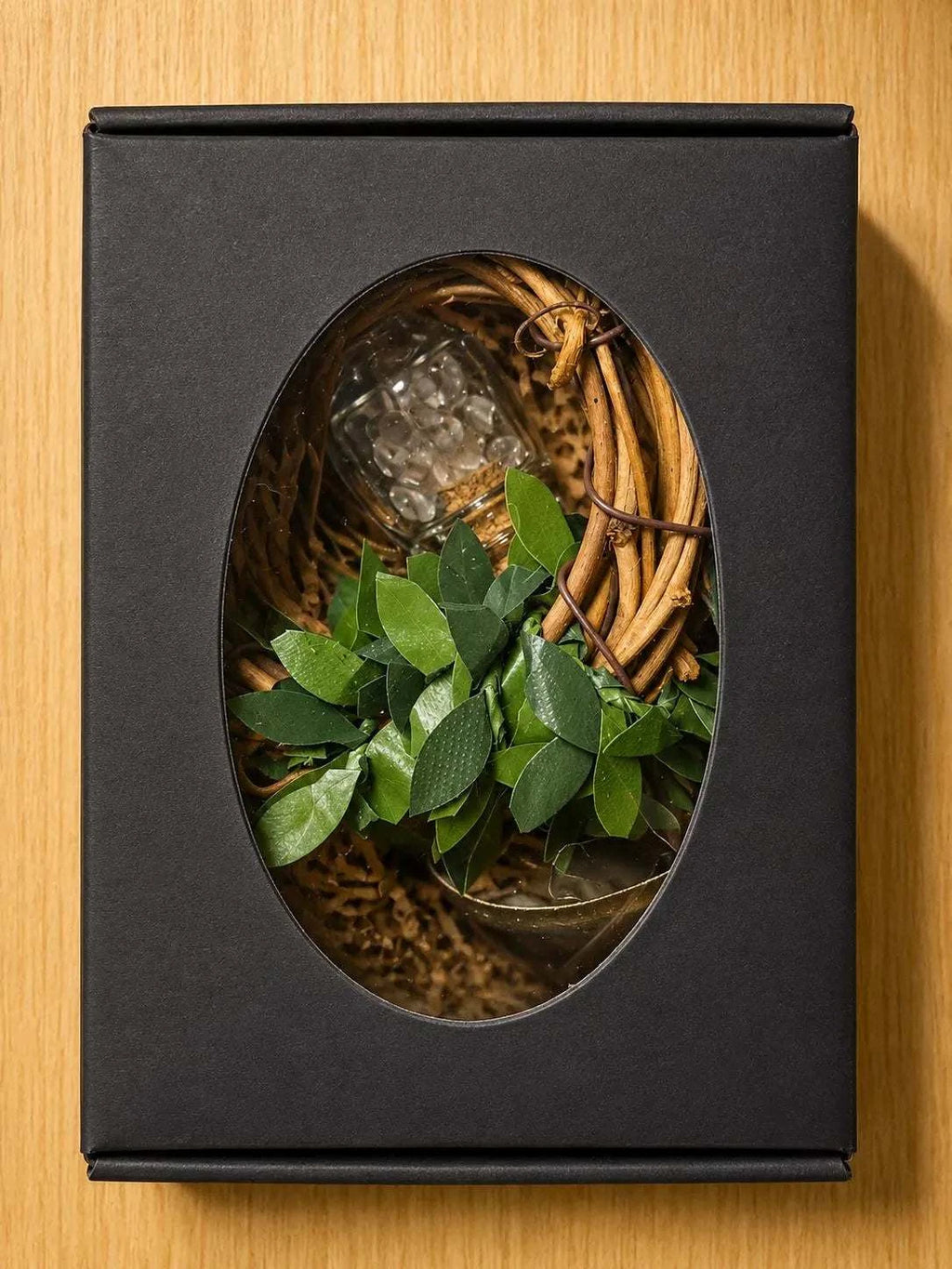 Threshiold Bells set in a black box, showing a woven wreath, green leaves, three bells and a clear quartz vial